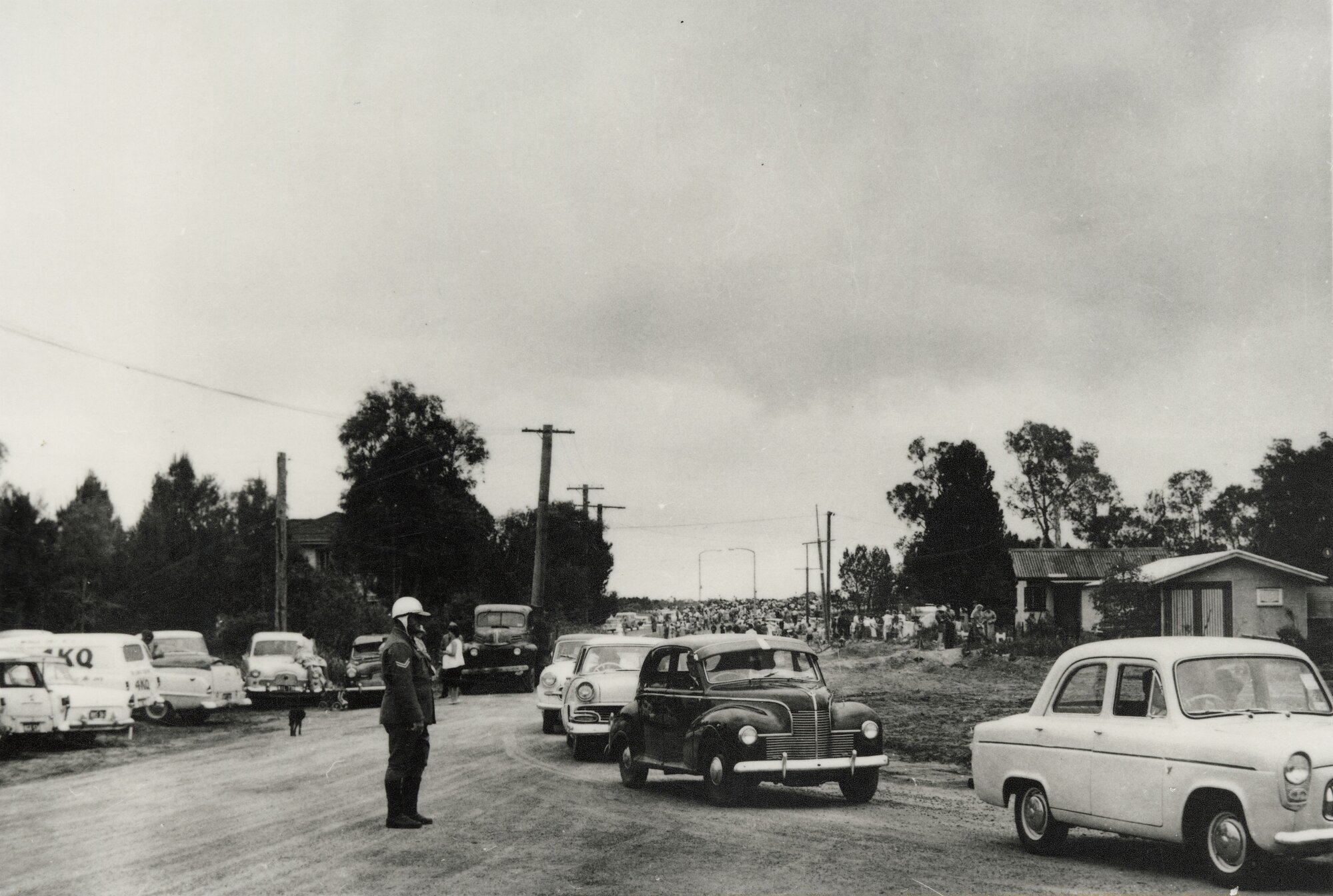 Cars and crowds dispersing from celebrations for the opening of the Bribie Island Bridge, 1963