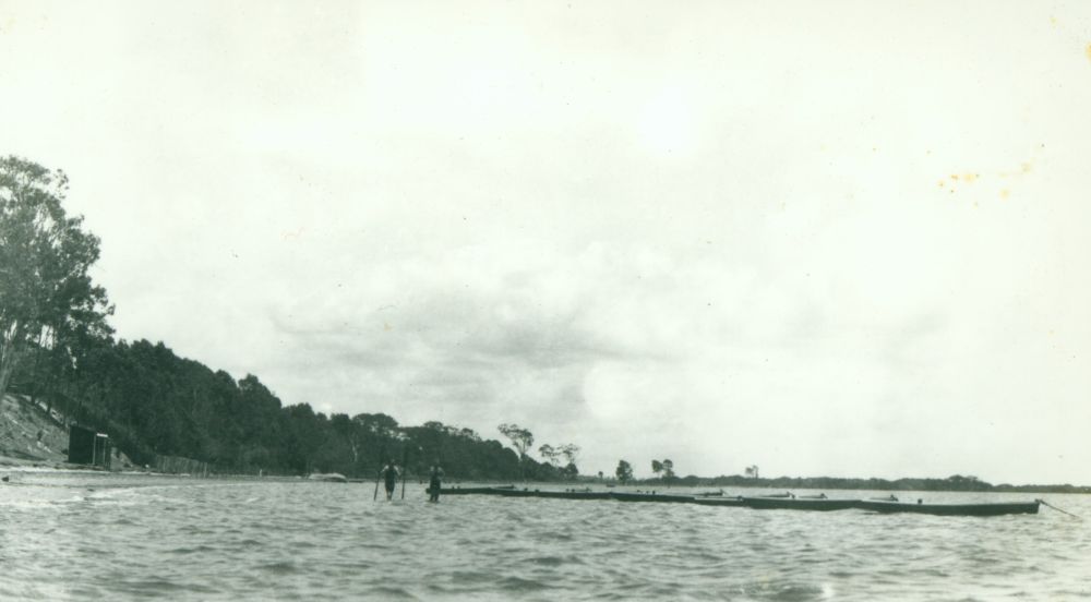 Two men standing in the water near the hire boats