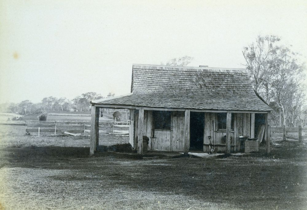 Small hut with fenced paddocks in the background