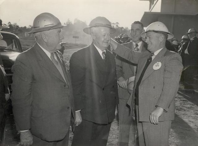 Three men in suits wearing hard hats