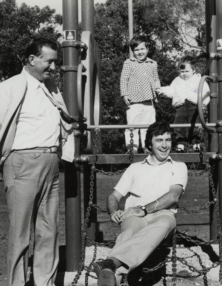Cr Alex Barr standing near playground equipment, ca. 1980