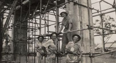 Four men wearing hard hats on scaffolding