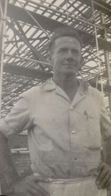 Man standing in front of mill construction