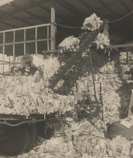 Unloading bales of waste paper on to conveyor belt