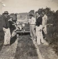 Five men on a track standing in front of a Land Rover