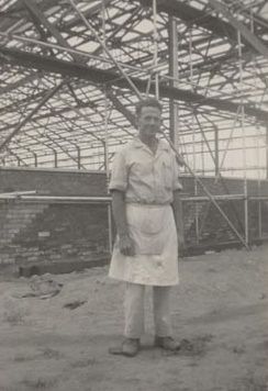 Staff member wearing apron in front of Mill construction