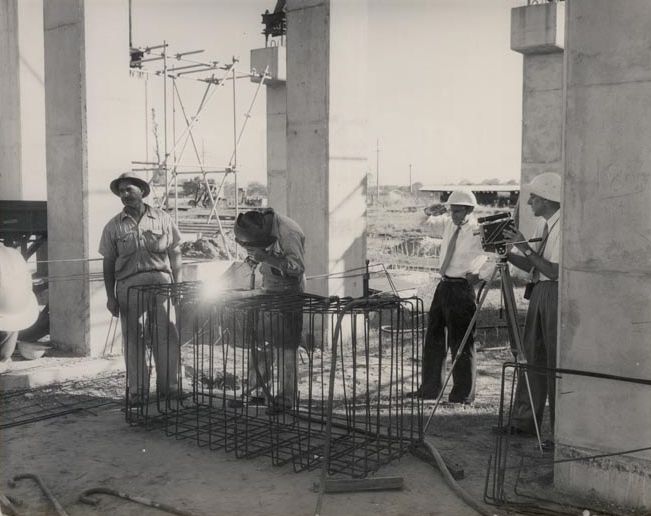 Worker welding with onlookers watching