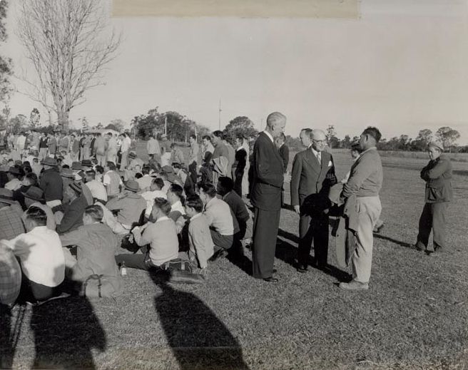 Workers sitting on grass in front of Mill