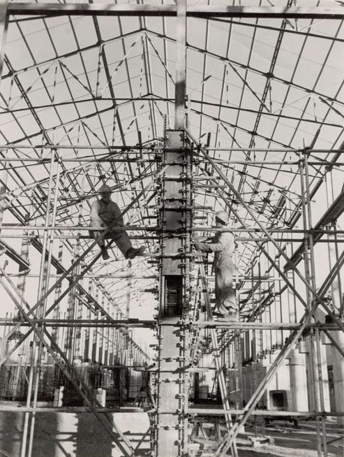 Two workers working on a pylon of the Mill building