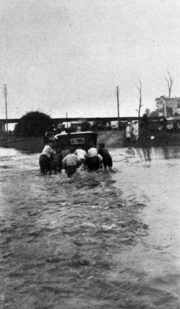 Pushing a motor vehicle through floodwaters over the North Pine River Bridge in 1927