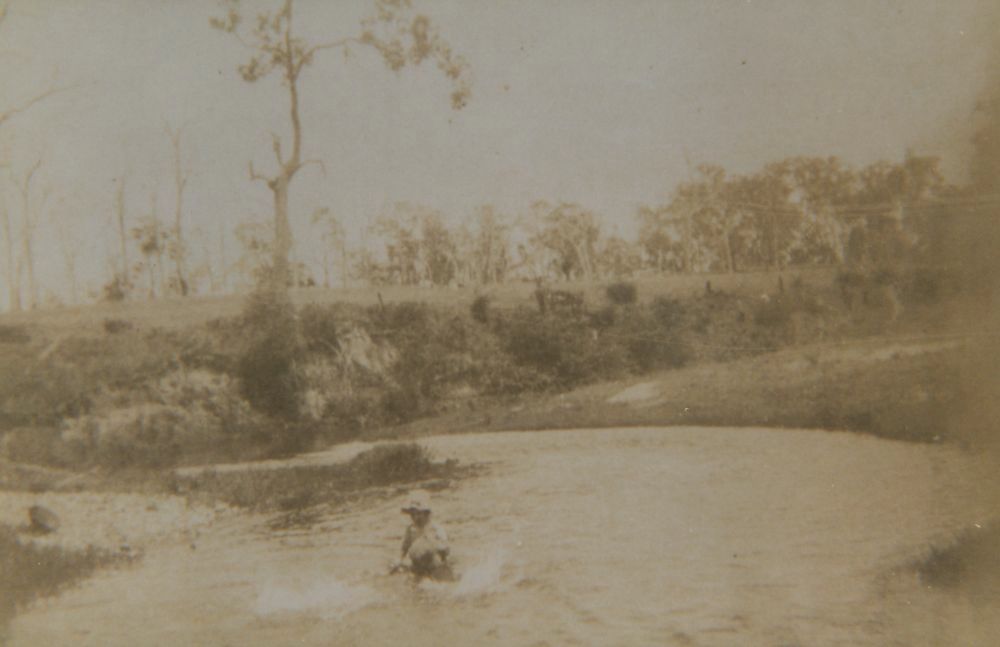 A child playing in the shallows near a bend in the North Pine River, 1920s