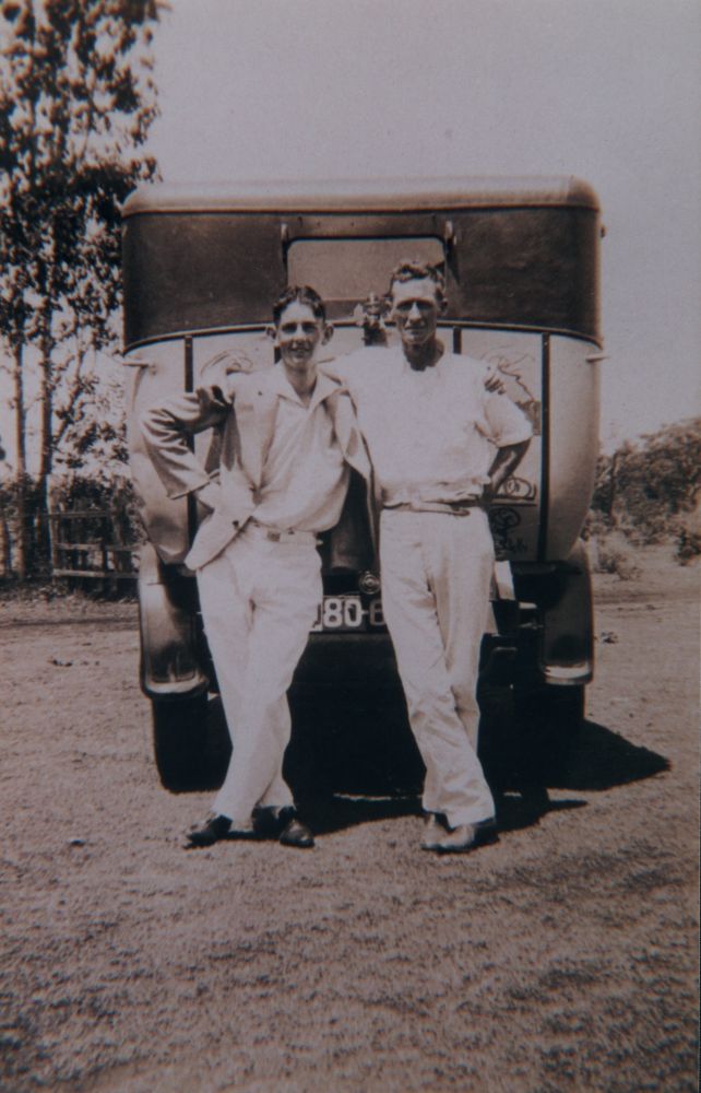 Two men standing at rear of a car, 1930