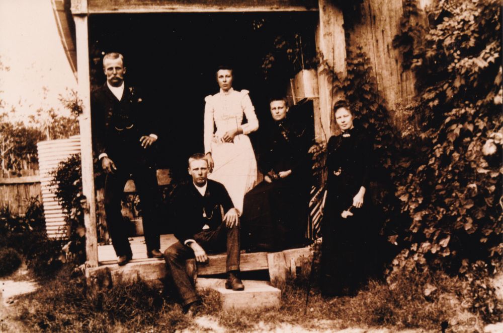 Group of people standing on the verandah of a house