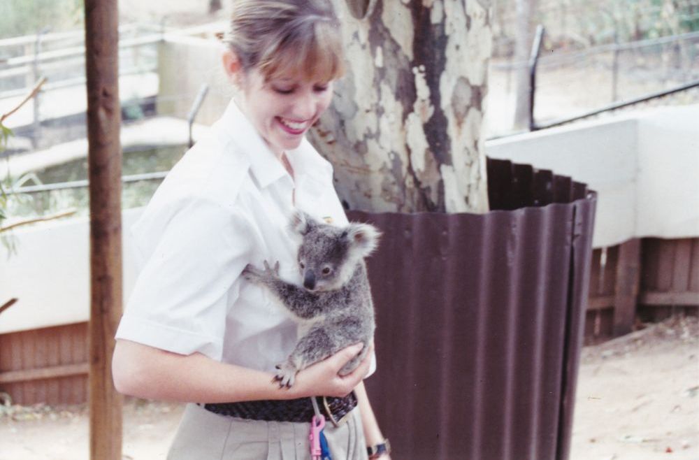 Woman holding baby koala (joey), ca. 1990