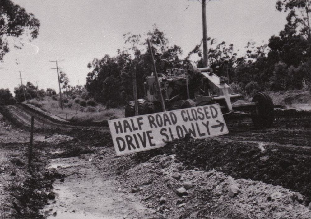 A worker using a grader as part of roadworks