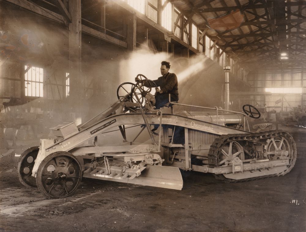 Man sitting on an Armstrong Holland Champion Queenslander grader, ca. 1930