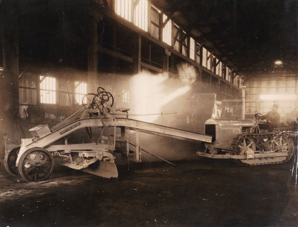 Man sitting on an Armstrong Holland Champion Queenslander grader, ca. 1930