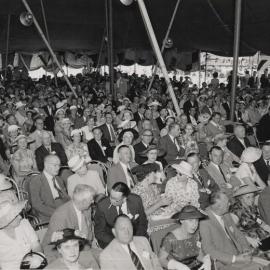 A large crowd sitting under a tent