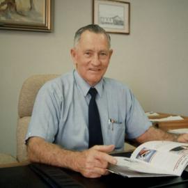 Cr J.T. (Tom) McLoughlin sitting at his desk in the Mayor's office