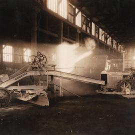 Man sitting on an Armstrong Holland Champion Queenslander grader, ca. 1930