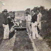 Five men on a track standing in front of a Land Rover